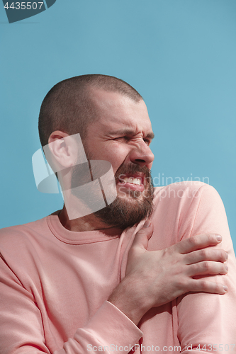 Image of Young man overwhelmed with a pain in the shoulder.