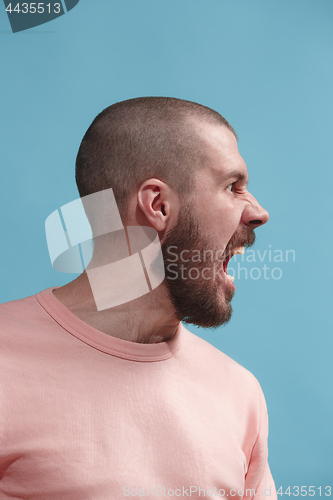 Image of The young emotional angry man screaming on blue studio background