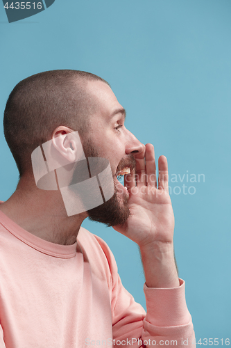 Image of Isolated on blue young casual man shouting at studio