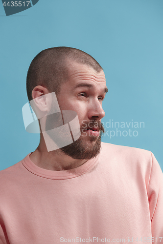 Image of Isolated on blue young casual man is boring at studio