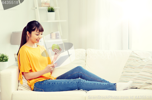 Image of happy asian woman with tablet pc and apple at home
