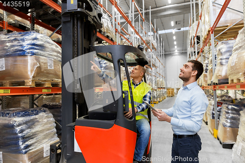 Image of men with tablet pc and forklift at warehouse