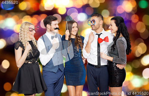 Image of happy friends with party props over festive lights