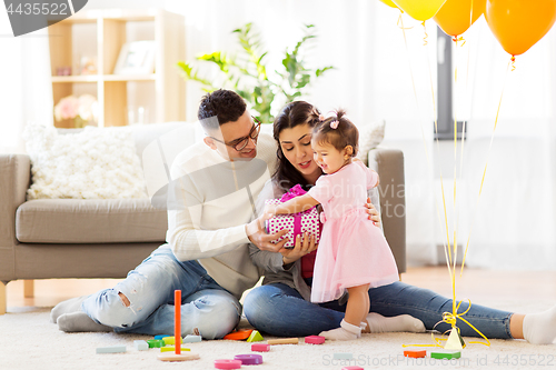 Image of baby girl with birthday gift and parents at home 