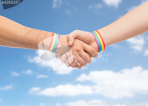 Image of hands with gay pride wristbands make handshake