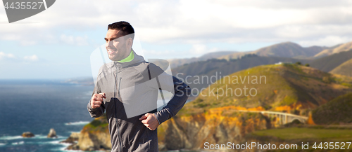 Image of happy young man running over big sur coast