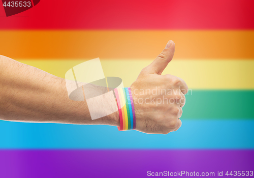 Image of hand with gay pride rainbow wristband shows thumb