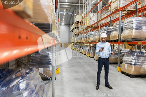 Image of businessman in helmet with smartphone at warehouse