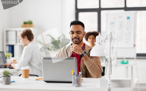 Image of happy indian man with laptop computer at office