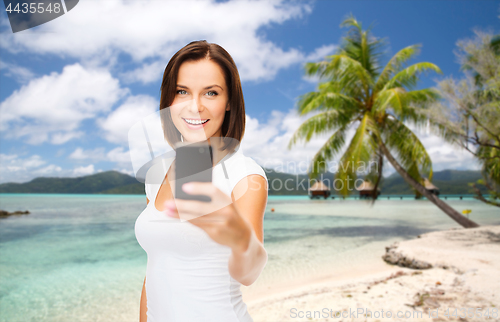 Image of woman taking selfie by smartphone on beach