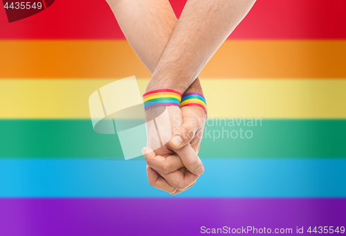 Image of hands of couple with gay pride rainbow wristbands