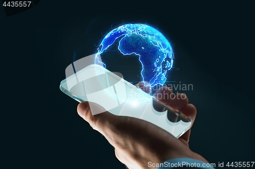 Image of hand with smartphone and earth hologram