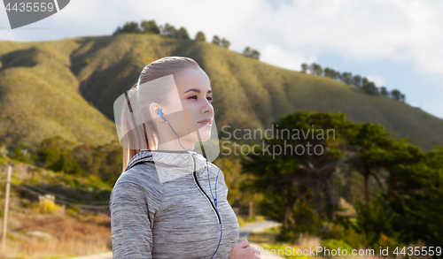 Image of woman with earphones running over big sur hills