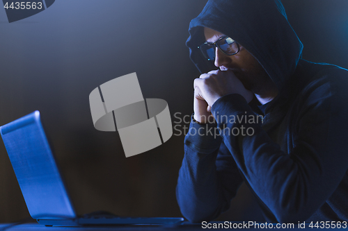 Image of hacker with laptop computer in dark room