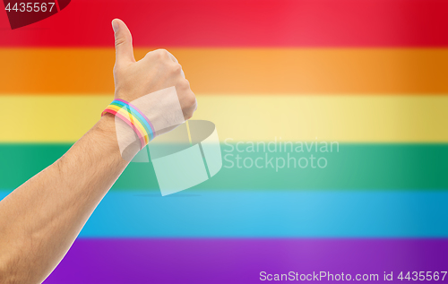 Image of hand with gay pride rainbow wristband shows thumb