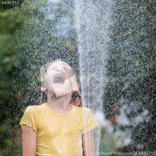 Image of Happy little girl pouring water from a hose.