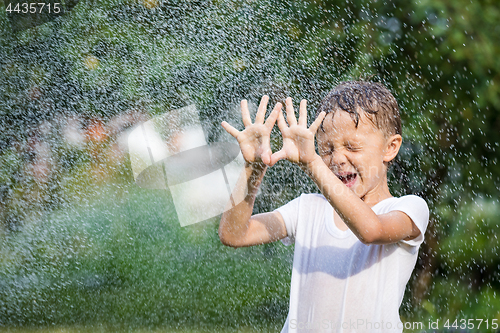 Image of Happy little boy pouring water from a hose.