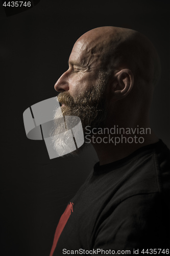 Image of a bearded man with closed eyes side view and dark background