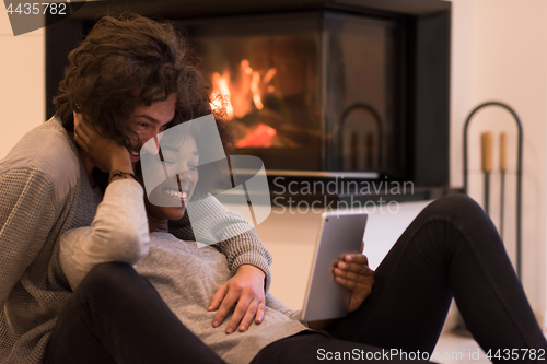 Image of multiethnic couple using tablet computer on the floor