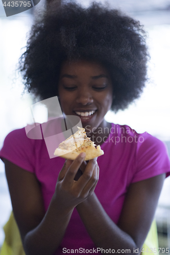 Image of woman with afro hairstyle eating tasty pizza slice