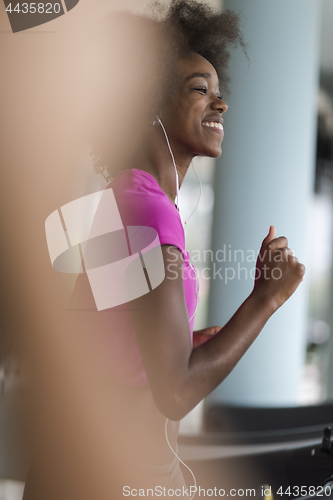 Image of afro american woman running on a treadmill