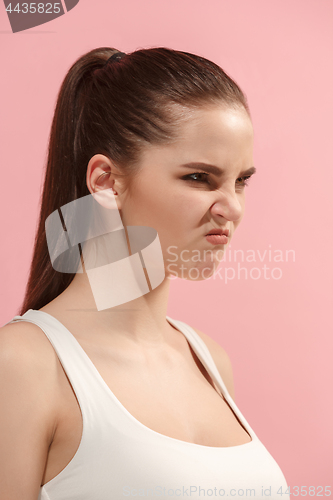 Image of Portrait of an angry woman looking at camera isolated on a pink background