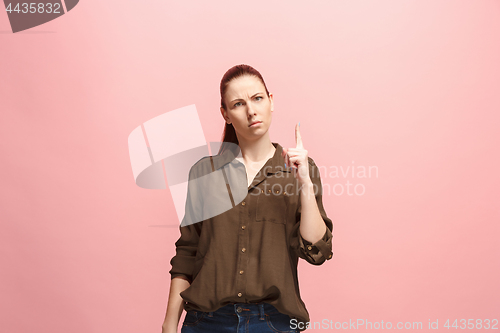 Image of The serious business woman standing and looking at camera against pink background.