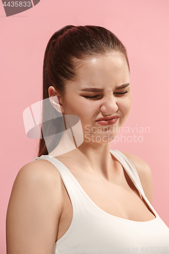 Image of Young woman with disgusted expression repulsing something, isolated on the pink