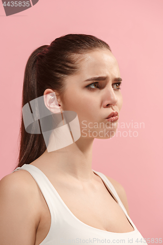 Image of The young woman is looking sad on the pink background.