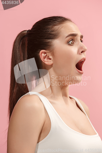 Image of The young woman is looking surprising on the pink background.