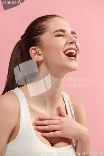 Image of The happy woman standing and smiling against pink background.