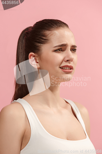 Image of The young woman is looking sad on the pink background.