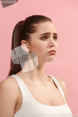 Image of The young woman is looking sad on the pink background.