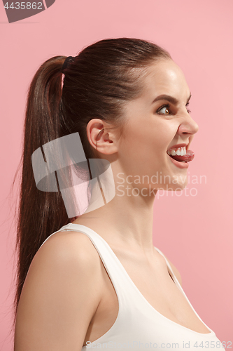 Image of The young woman is looking crazy on the pink background.