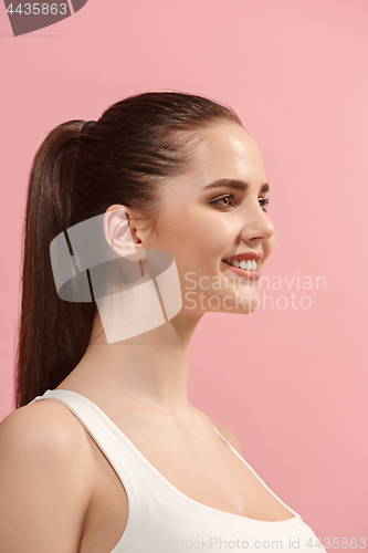 Image of The happy woman standing and smiling against pink background.