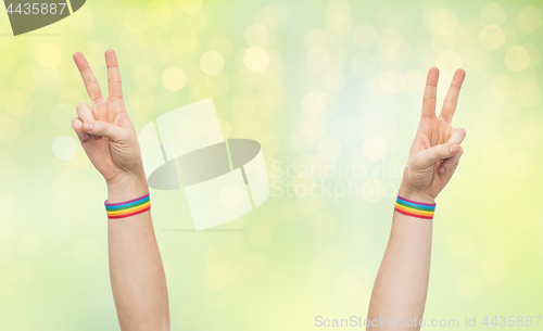 Image of hands with gay pride rainbow wristbands make peace