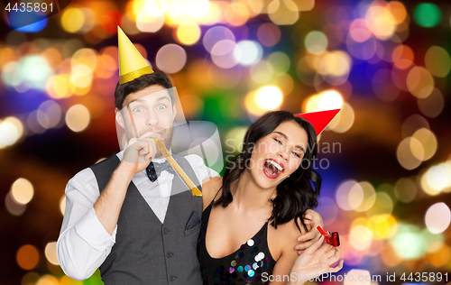 Image of happy couple with party blowers having fun