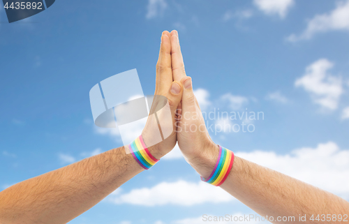 Image of hands with gay pride wristbands make high five