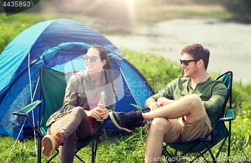 Image of happy couple drinking beer at campsite tent