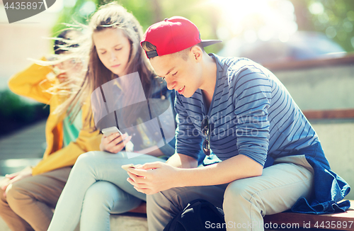 Image of happy teenage friends with smartphones outdoors