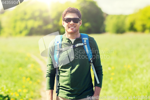 Image of happy young man with backpack hiking outdoors