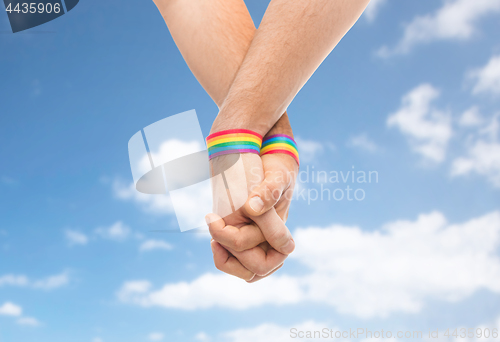 Image of hands of couple with gay pride rainbow wristbands