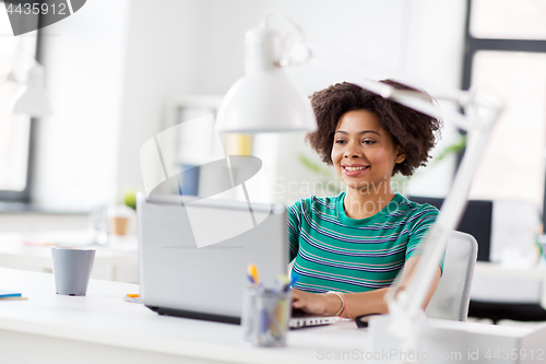 Image of happy african woman with laptop computer at office