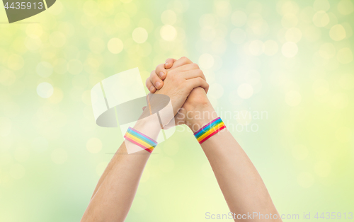 Image of hands with gay pride wristbands in winning gesture