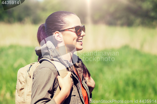 Image of happy young woman with backpack hiking outdoors