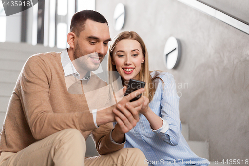 Image of man and woman with smartphone at office stairs