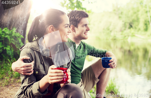 Image of happy couple with cups drinking in nature