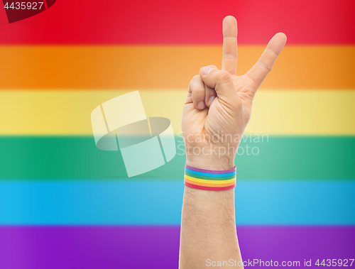 Image of hand with gay pride rainbow wristband make peace