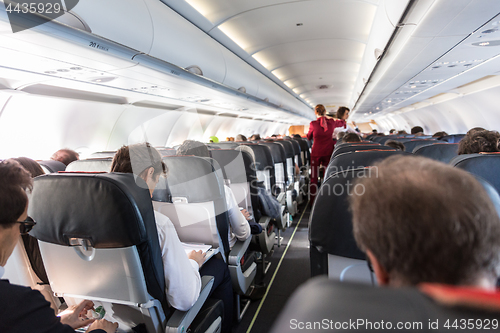 Image of Interior of commercial airplane with passengers on their seats during flight.