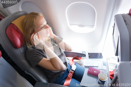 Image of Woman listening to music on smart phone on commercial passengers airplane during flight.